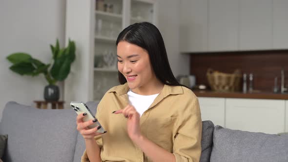 Cute Asian Woman Looking at the Smartphone in Her Hands