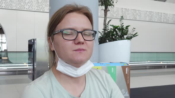 Masked Woman is Sitting in the Hall of the Room with a Dissatisfied Face alt