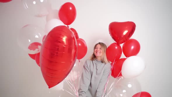 an Blonde Woman Dances and Has Fun with Balloons on a White Background alt