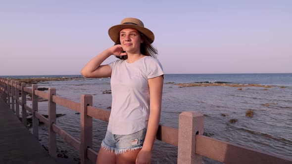 Teen girl standing on wooden bridge by the sea alt
