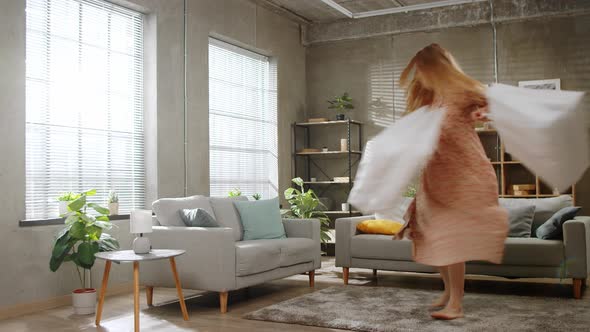 Young Beautiful Woman Happily Spins in the Living Room with White Packages After Shopping alt