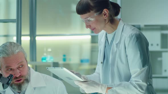 Senior Scientist Doing Lab Experiment with Female Assistant alt