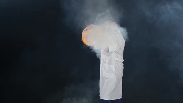 Man Chemist in Uniform and Protective Glasses Making Interesting Trick with Air Smoke Bubble, Rounds alt
