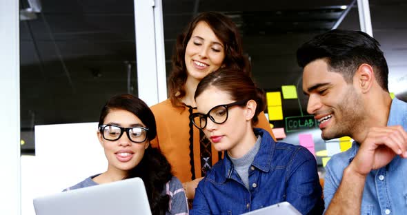 Smiling executives discussing over laptop during meeting alt