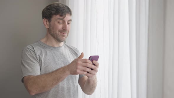 Portrait of Happy Confident Man Swiping Smartphone Screen Shaking Head Yes Looking at Camera and alt