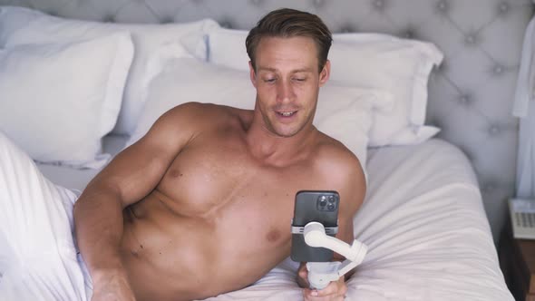Portrait of Young Caucasian Man Uses Smartphone with Gimbal Stabilizer alt