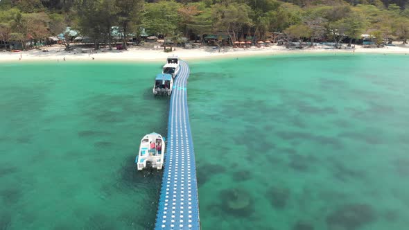 Approaching sand beach of Coral Island, Thailand. Fly over pier and boats alt