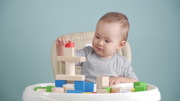 A joyful baby of 15-25 months is learning to play with a wooden block constructor. alt