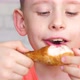 portrait of a caucasian boy 8-9 years old eating fried chicken legs, closing his eyes in pleasure. t - VideoHive Item for Sale