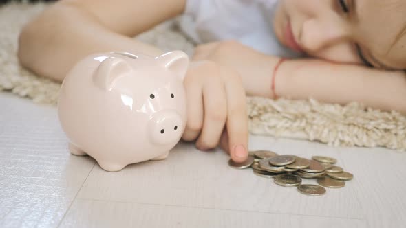 Little girl blond put coins in a piggy bank. Saving money concept alt