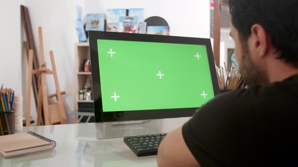 Bearded Man Looking at a Green Screen on His Computer alt