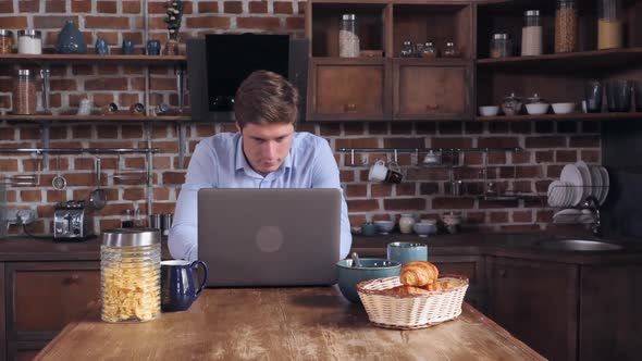 Young Guy Reading News on Computer in the Morning alt