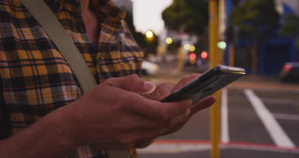 Caucasian male using his tablet in a street in the evening alt