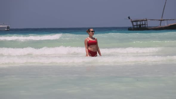 Young Woman in Red Swimsuit Resting and Bathing Into the Ocean on Paradise Beach alt