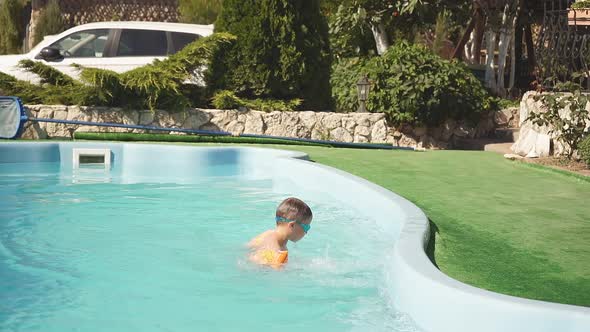 Happy Child in Armbands Swims in the Pool on a Sunny Clear Day
