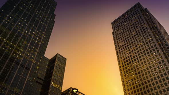 Day to night of a large office building with the lights coming on time lapse