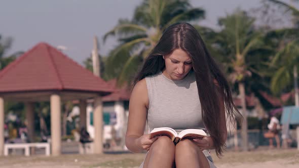 Pretty Lady with Long Hair Waved By Wind Sits and Reads alt