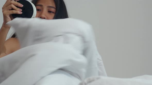 Asian young woman shocked as he wake up late for an appointment on bed in bedroom at home alt