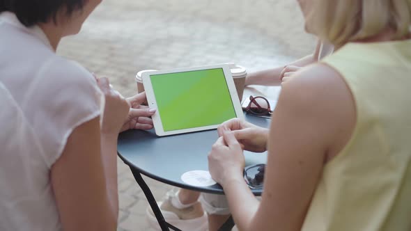 Shooting Over Shoulder of Positive Mid-adult Women Surfing Internet on Tablet. Cheerful Friends alt
