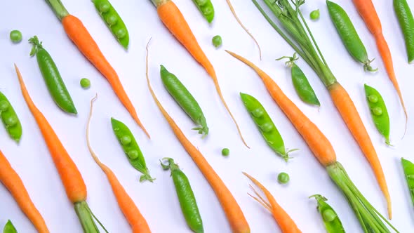 Rotating Background of Young Carrots and Green Peas on a White Background Fresh Vegetables the