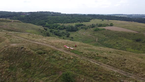 a Man with a Parachute in a Hilly Landscape alt
