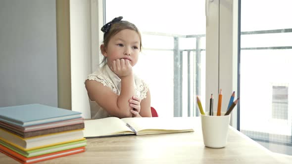 Little Elementary School Student Sits Thoughtfully at Her Desk, Resting Her Head on Her Hand. Back alt