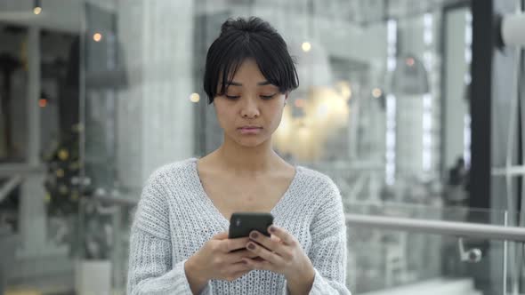 Middle Shot of Asian Female Walking with a Phone on Windows Background