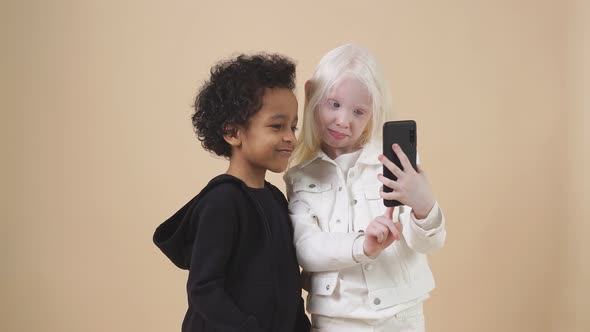 Funny Children with Diverse Appearance Pose i Studio with a Smartphone in Hands alt