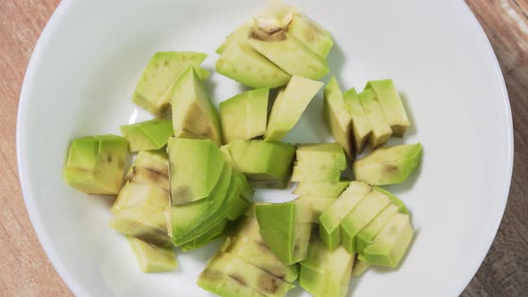 Adding Chopped Slices of Raw Avocado in a White Bowl Close-up, Stop Motion