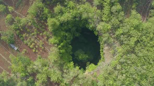 Top down drone shot view descending above the Jomblang Cave in Yogyakarta Indonesia alt