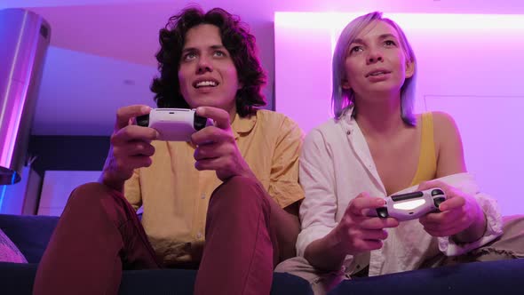 Smiling Couple Holding Gamepads Playing Video Game at Home. Low Angle Shot of Young People Spending alt
