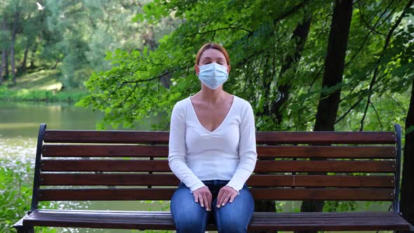 Pandemic, Coronavirus Quarantine. Young Woman Sits on a Park Bench Alone During an Epidemic alt