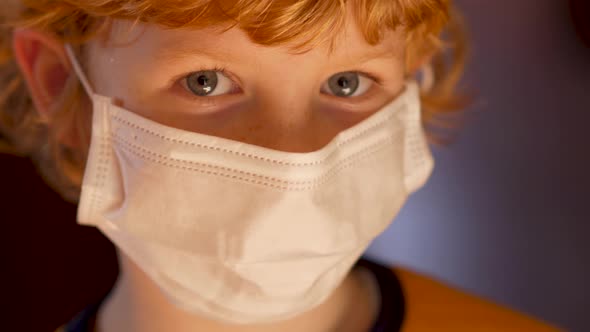 Blond boy with a medical mask on his face against coronavirus