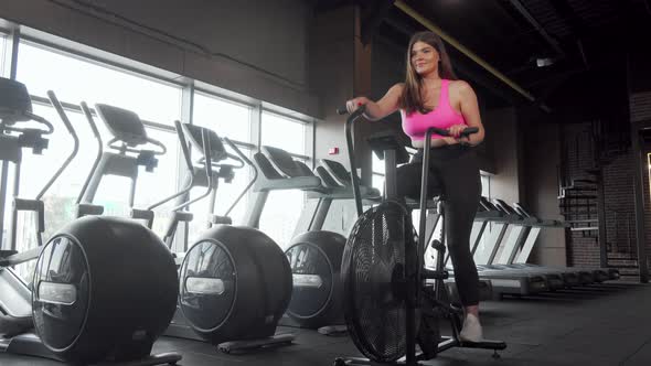 Gorgeous Happy Plus Size Woman Exercising on Air Bike and Cycling at the Gym