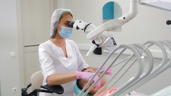 Female Dentist Treating Male Patient Using White Proffessional Microscope alt