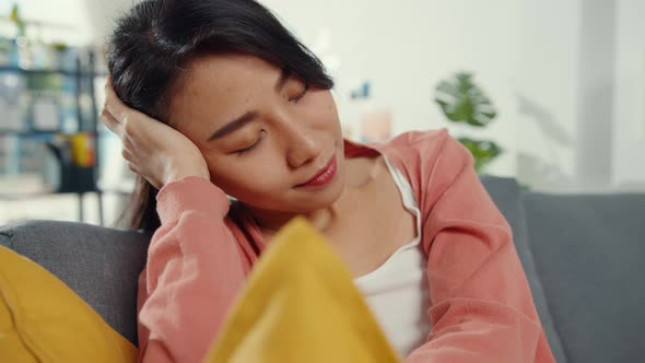 Beautiful Asian lady feel relax lay down on sofa with pillow at living room alt