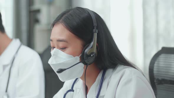 Close Up Of An Asian Woman Doctor In Masks Working As Call Centre Agent Speaking To Customer alt