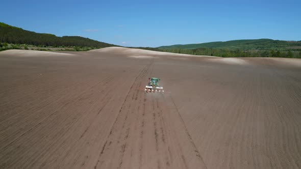 Field with picturesque hills and a moving tractor alt