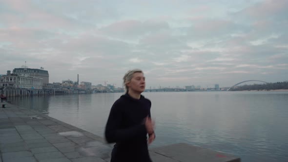 Sportswoman Running Near River in Evening alt