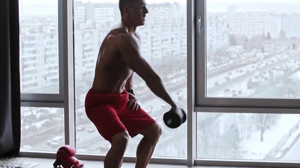 Muscular Shirtless Man Doing Situps and Pumping Up His Muscles with Dumbbells in His Hand alt