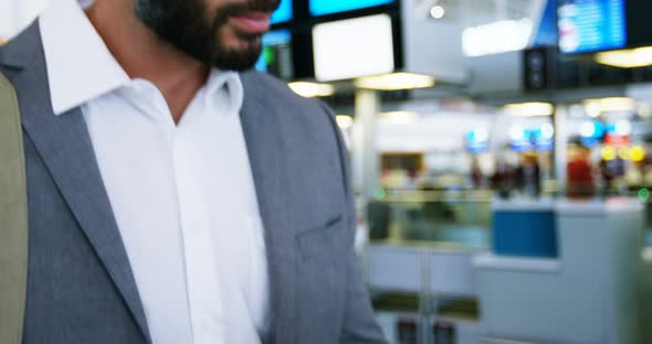 Businessman using mobile phone while checking his boarding pass alt