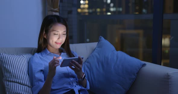 Woman use of mobile phone online at night inside home alt