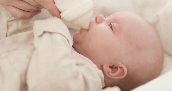 Mother's Hands Hold a Bottle of Milk