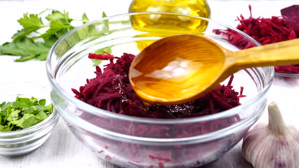 Olive oil is added to the grated beetroot salad in the salad bowl
