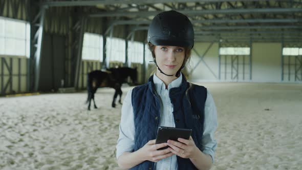 Portrait of Female Jockey with Tablet in Riding Arena alt