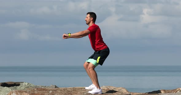 Athletic fit sportsman man in sports clothes warm up training at sunrise sun over sea beach.