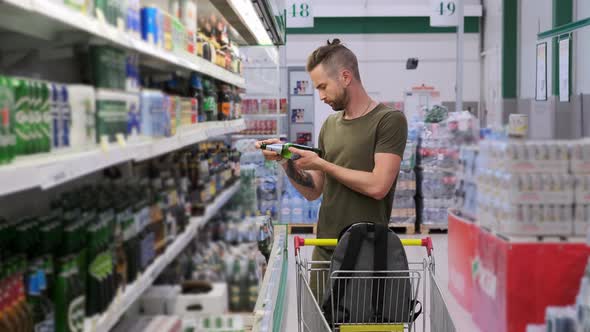 Man is Buying Alcoholic and Nonalcoholic Beer in Supermarket alt