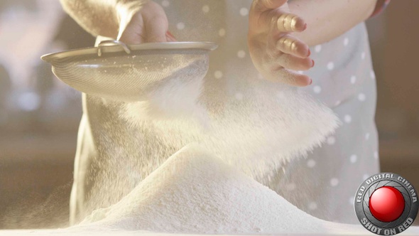 Woman Sifting Flour With A Sifter In The Kitchen With Sun Shining In Slow Motion Shot On Red Camera alt