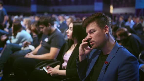 Business Man Talking on Pnone Crowded Audience. People Speak Mobile with Partner alt