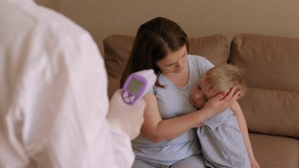 A Doctor Examines a Family with Symptoms of Coronavirus at Home alt